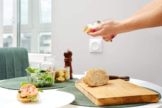 Hands of unrecognizable woman spreading cream cheese on sandwich
