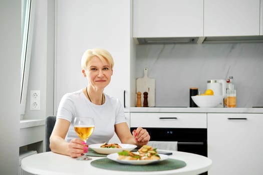 Portrait of positive senior woman in the kitchen having breakfast
