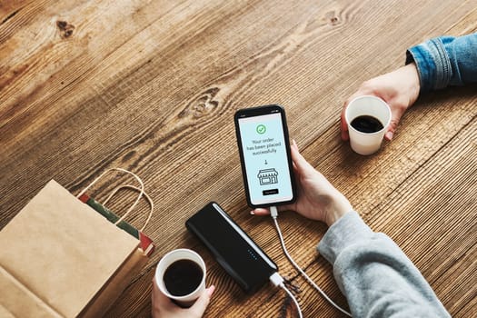 Online shopping. Paying online. Ordering product in online shop using smartphone. Payment confirmation on screen. Online banking. Paying for online shopping while charging mobile phone from powerbank in coffee shop