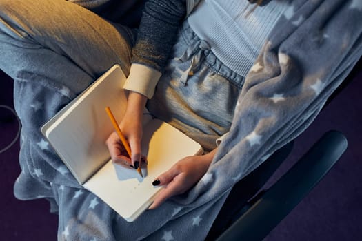 Student learning at home. Young woman making notes, reading and learning from notepad sitting in bed at home during quarantine