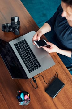 Female photographer working on photos on laptop and camera. Woman editing retouching browsing photos working as a freelancer sitting at desk