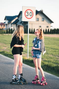 Teenage smiling happy girls having fun rollerskating, spending time together on summer day