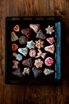 Christmas gingerbread cookies in many shapes decorated with colorful frosting, sprinkle, icing, chocolate coating, toppers, put on tray