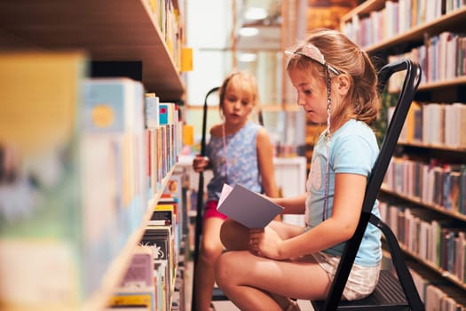 Schoolgirls looking for audio books in school library. Students choosing set books. Elementary education. Doing homework. Learning from books. Back to school
