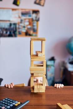 Little girl preschooler playing with wooden blocks toy building a tower. Concept of building a house