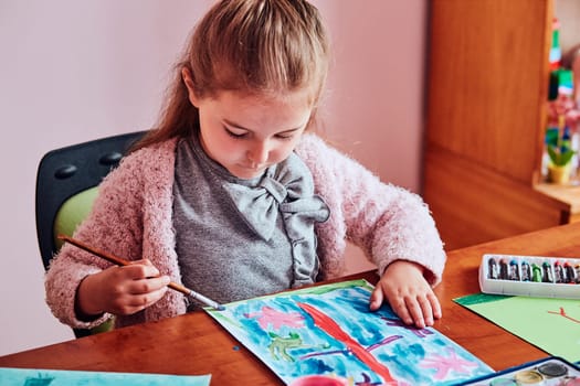 Little girl preschooler painting a picture using colorful paints and crayons. Child having fun making a picture during an art class in the classroom