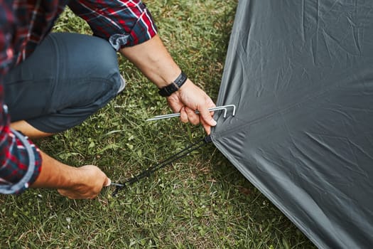 Man putting up a tent at camping during summer vacation. Preparing campsite to rest and relax. Spending vacations outdoors close to nature