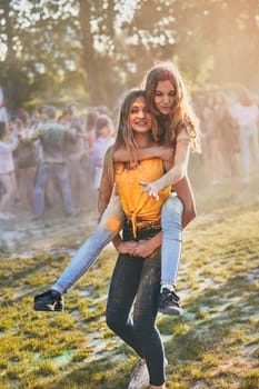 Portrait of happy smiling young girls with colorful paints on faces and clothes. Two friends spending time on holi color festival