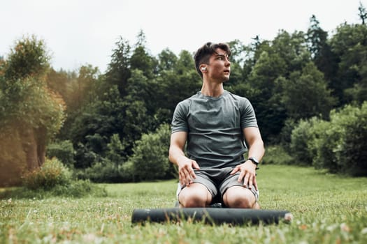 Young man doing exercises outside on grass during his calisthenics workout. Teenager training outdoors