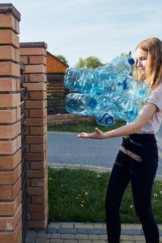 Young woman throwing out empty used plastic water bottles into trash bin. Collecting plastic waste to recycling. Concept of plastic pollution and too many plastic waste. Environmental issue