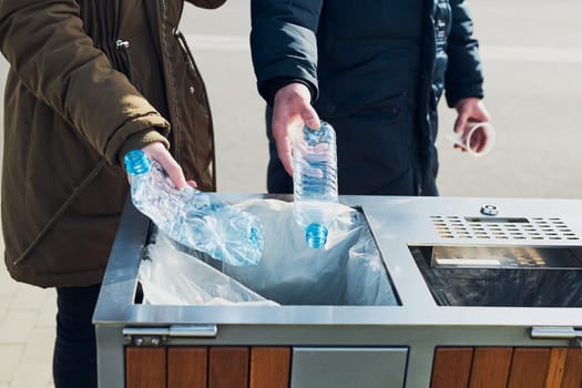Woman and man throwing a plastic bottles to trash. Plastic waste to recycling. Concept of plastic pollution and recycling plastic waste. Environmental issue. Environmental damage. Real people, authentic situations