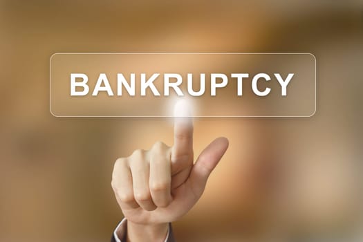 business hand pushing bankruptcy button on blurred background
