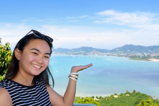 Women tourist smiling are happy to show his hand inviting them to see the beautiful landscape of sea on Khao-Khad mountain viewpoint famous attractions in Phuket Province, Thailand