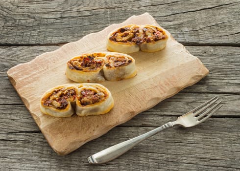 Stuffed puff pastry pig's ears on a board with fork