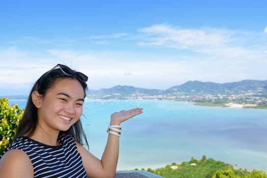 Women tourist smiling are happy to show his hand inviting them to see the beautiful landscape of sea on Khao-Khad mountain viewpoint famous attractions in Phuket Province, Thailand