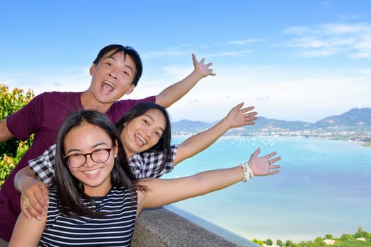 Family of tourists smiling are happy and show their hands invite to see the beautiful landscape of sea on Khao-Khad mountain viewpoint famous attractions in Phuket Province, Thailand