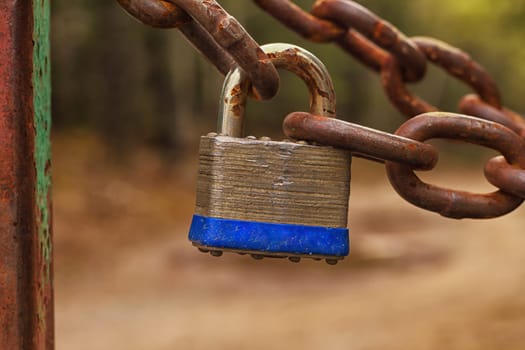 Silver metal lock on a rusty chain.