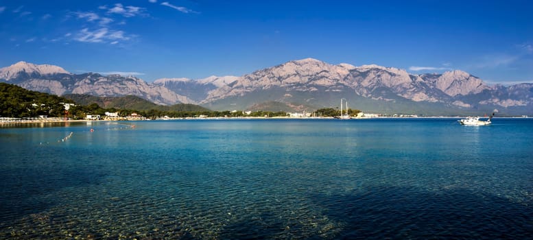 Kemer Antalia nice view of the sea. Beach Kemer Antalia with sand and mountains, the sea with the ship. Beautiful harbor near the sandy beach.