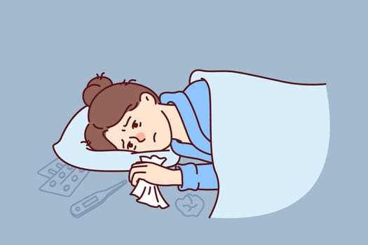 Woman sick with flu lies under blanket with handkerchief in hand near thermometer and medicines to treat fever. Sick girl needs qualified medical care due to outbreak of viral infection