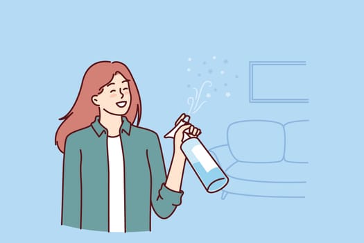Woman uses air freshener to get rid of unpleasant smell in apartment after cleaning. Housewife girl stands in living room with air freshener spraying fragrance to create comfortable environment