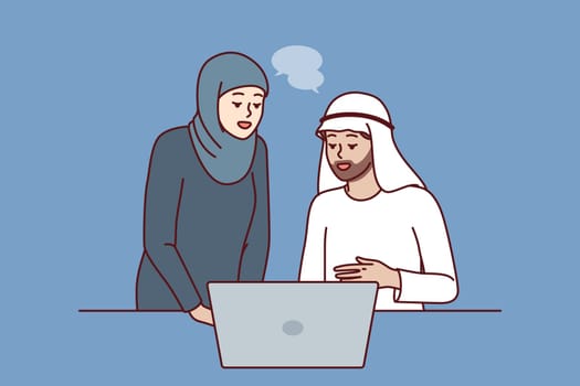 Office workers in Arabic clothing discussing business presentation from laptop. Arabic man and woman work together in corporation in dubai or emirates and conduct business negotiations via internet.
