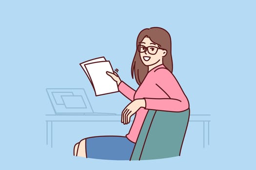 Successful woman office worker holds papers and sits at table with laptop making career as accountant or lawyer. Successful businesswoman turning around and looking at camera while doing paperwork