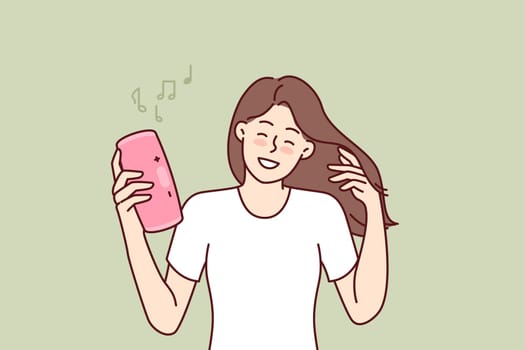 Woman with wireless portable speaker smiling enjoying loud rhythmic music of favorite rock band. Young girl with pink portable speaker enjoys listening to playlist, creating disco atmosphere