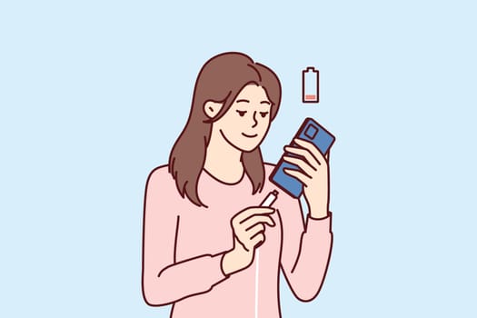 Woman holding smartphone uses cable to charge battery after seeing red indicator of dead accumulator. Girl with mobile phone connects type-c or usb mini wire for fast battery charging