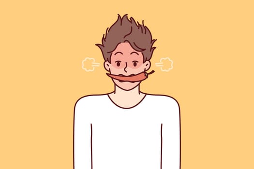 Man with hot chili or in teeth blushes and blows smoke from ears for metaphor of anger and negative emotions. Young guy with shaggy hair with hot chili pepper in mouth looks at screen