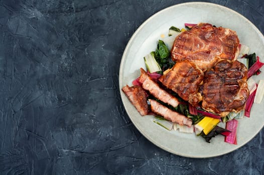 Fried meat steak and fresh herb salad on dark slate background.Copy space.