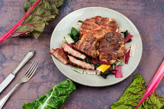 Fried meat steak and fresh herb salad on dark slate background.Copy space.