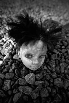 Detail of old creepy doll thrown in the trash