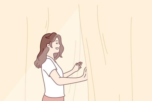 Smiling woman looks out window opening curtains and enjoying rays of summer morning sun. Girl opens curtains rejoicing at new sunny day after waking up in morning or dreams of going for walk