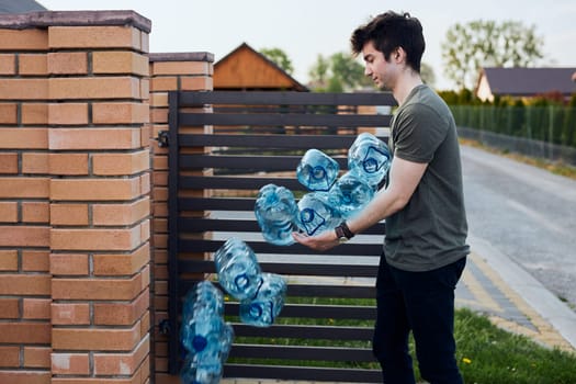 Young man throwing out empty used plastic water bottles into trash bin. Collecting plastic waste to recycling. Concept of plastic pollution and too many plastic waste. Environmental issue