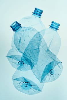 Empty plastic squashed bottles over blue background. Collecting plastic waste to recycling. Concept of plastic pollution and too many plastic waste. Copy space for text