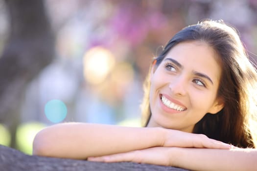 Front view portrait of a beauty woman looking sideways in a park