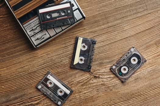 Compact cassette tapes and cassette recorder on wooden table. Retro music style. 80s music party. Vintage style. Analog equipment. Stereo sound. Back to the past