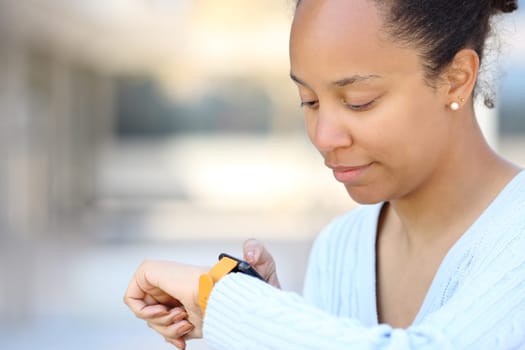 Black beautiful woman using smartwatch in the street