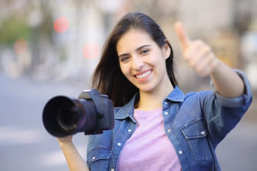 Happy photographer gesturing thumb up in the street