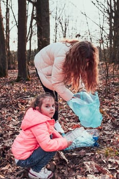 Family cleaning up a forest. Volunteers picking plastic waste to bags. Concept of plastic pollution and too many plastic waste. Environmental issue. Environmental damage. Responsibilitiy for environment. Real people, authentic situations