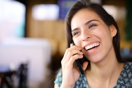 Happy woman laughing calling on phone sitting in a restaurant