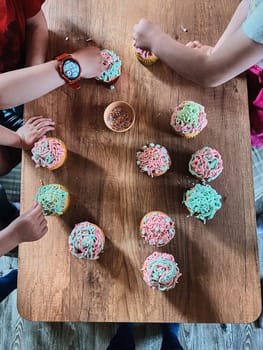 Group of children baking cupcakes, preparing ingredients, topping, sprinkles for decorating cookies. Kids cooking, working together in kitchen at home. Concept of happy family
