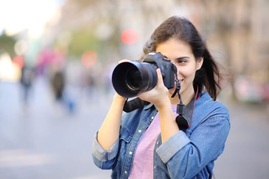 Happy photographer taking photos standing in the street with dslr camera