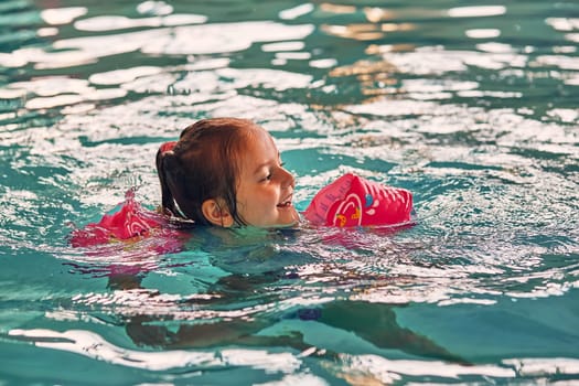 Little happy smiling girl playing in water in pool. Candid people, real moments, authentic situations