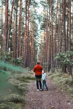 Mother and her little daughter walking in a forest during summer vacation trip. Family spending time together outdoors in nature