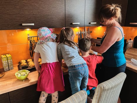 Group of children baking cupcakes, preparing ingredients, toppings, sprinkles for decorating cookies. Kids learning to cook, working together in kitchen at home. Concept of happy family