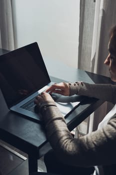 Focused businesswoman working remotely on her laptop computer contemplate managing her work sitting at the table in a cafe