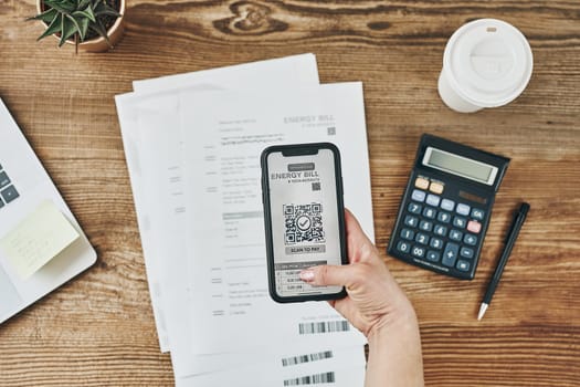 Woman paying for energy scanning QR code from bill. Making payment using QR scanner and fast secure payment system on smartphone. Business woman paying bills using express payment technology. Female using mobile phone and laptop. Making payment. Paying bills. Paying expenses online