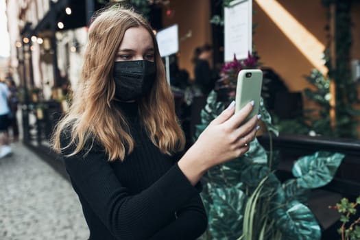 Young woman having video call talking while walking downtown wearing the face mask to avoid virus infection and to prevent the spread of disease in time of coronavirus