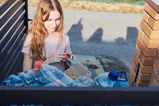 Young woman throwing out empty used plastic water bottles into trash bin. Collecting plastic waste to recycling. Concept of plastic pollution and too many plastic waste. Environmental issue